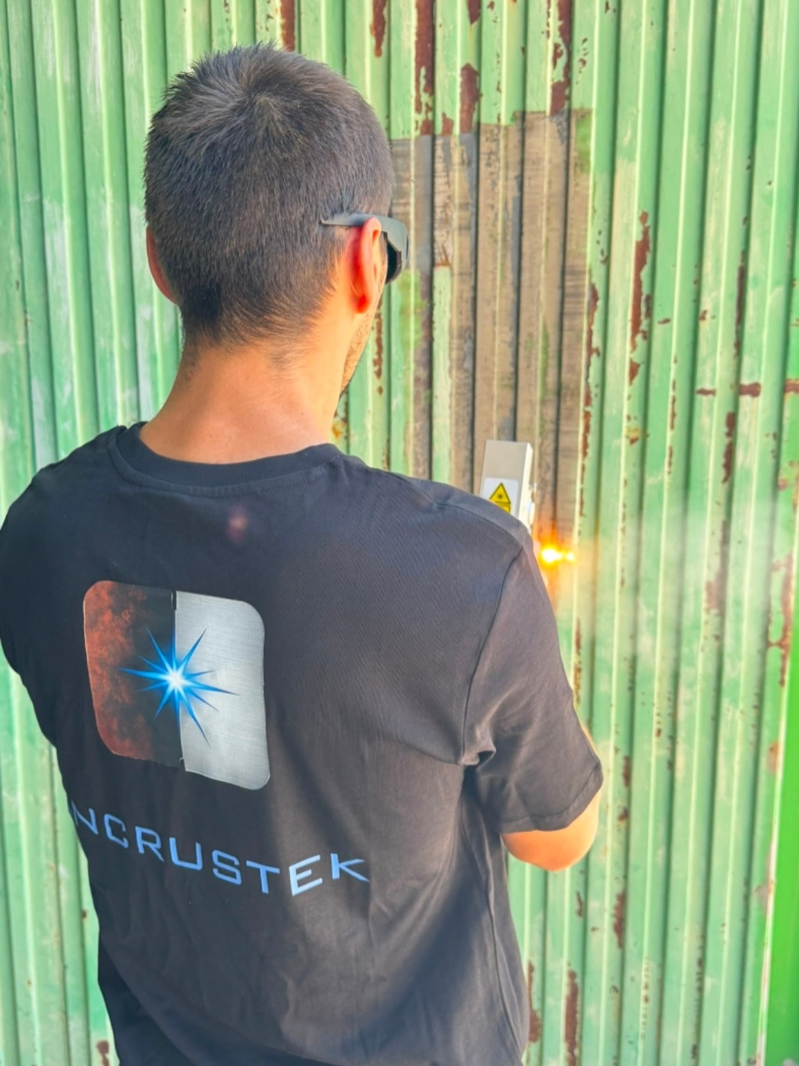 Técnico de INCRUSTEK limpiando con láser una puerta metálica oxidada